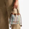 Dragsko-påse med handtag i flera färger och beige chevron-raffia med läderdetaljer Dragsko-påse med handtag i flera färger och beige chevron-raffia med läderdetaljer