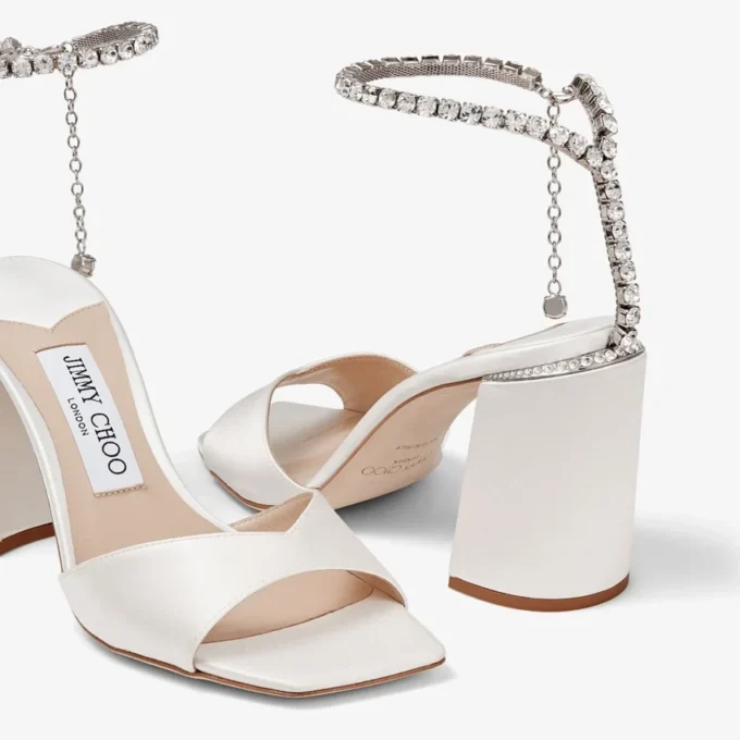 Saeda-sandal med blockklack 85 Sandaler i elfenbensfärgad satin med blockklack och kristallkedja Saeda-sandal med blockklack 85 Sandaler i elfenbensfärgad satin med blockklack och kristallkedja